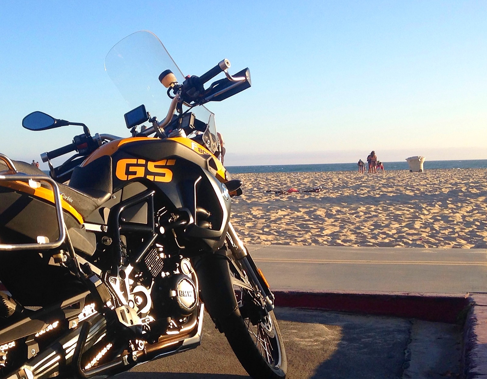 The motorcycle parked on the beach at sunset
