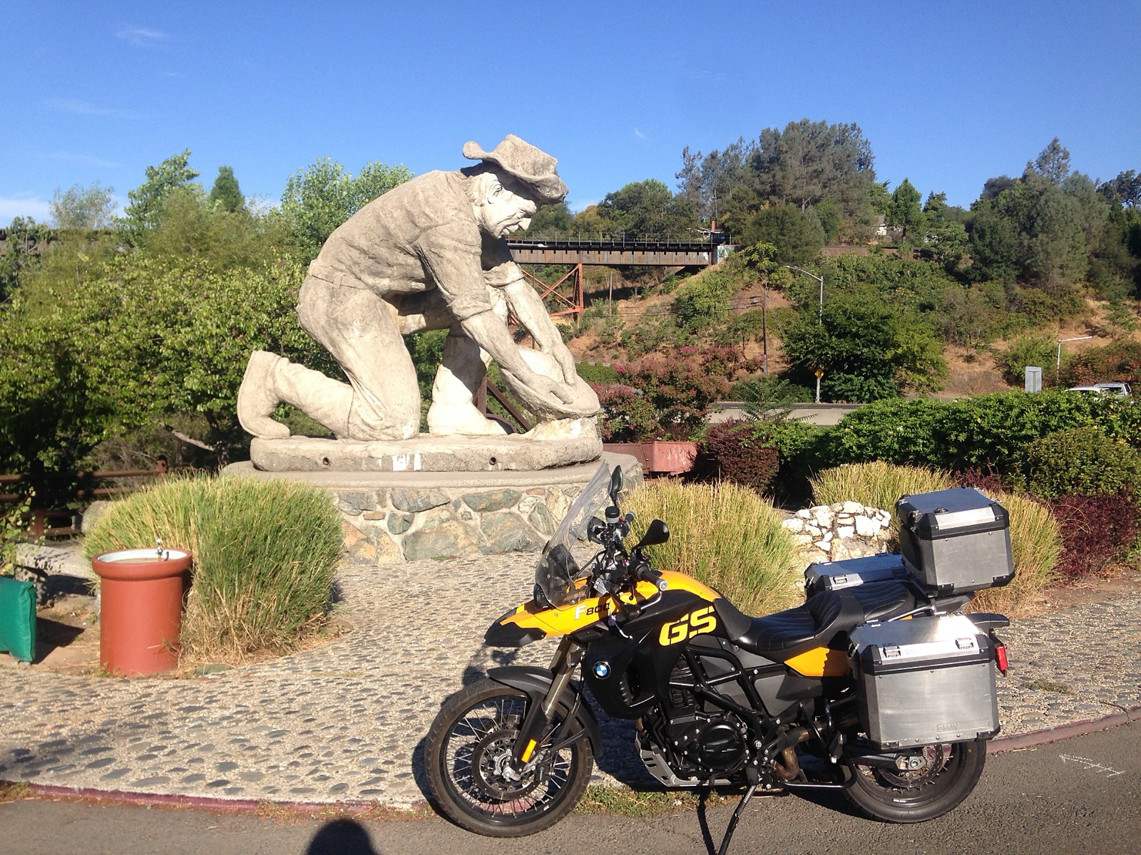 The motorcycle beside a stone statue of a gold miner in Auburn