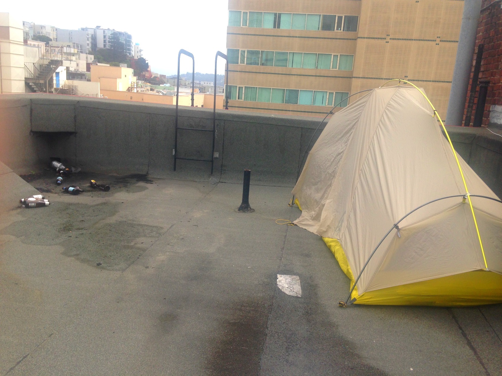A tent pitched on a concrete terrace between city buildings