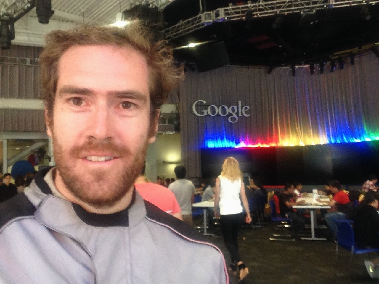 A selfie inside a Google canteen with the logo lit above a stage