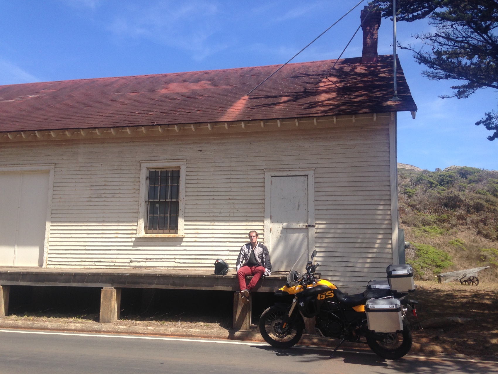 A long white timber building of the old fort with the motorcycle in front