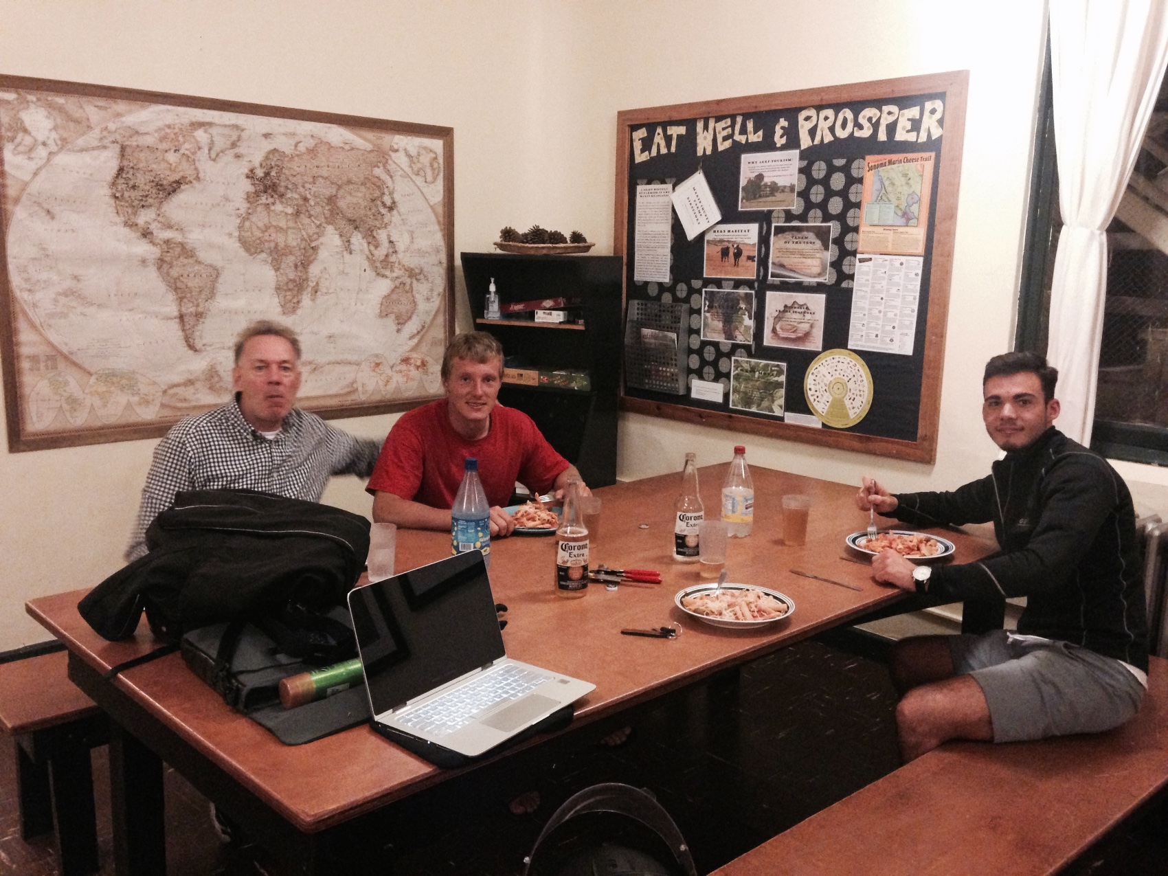 People around a table in a shared kitchen with a world map on the wall