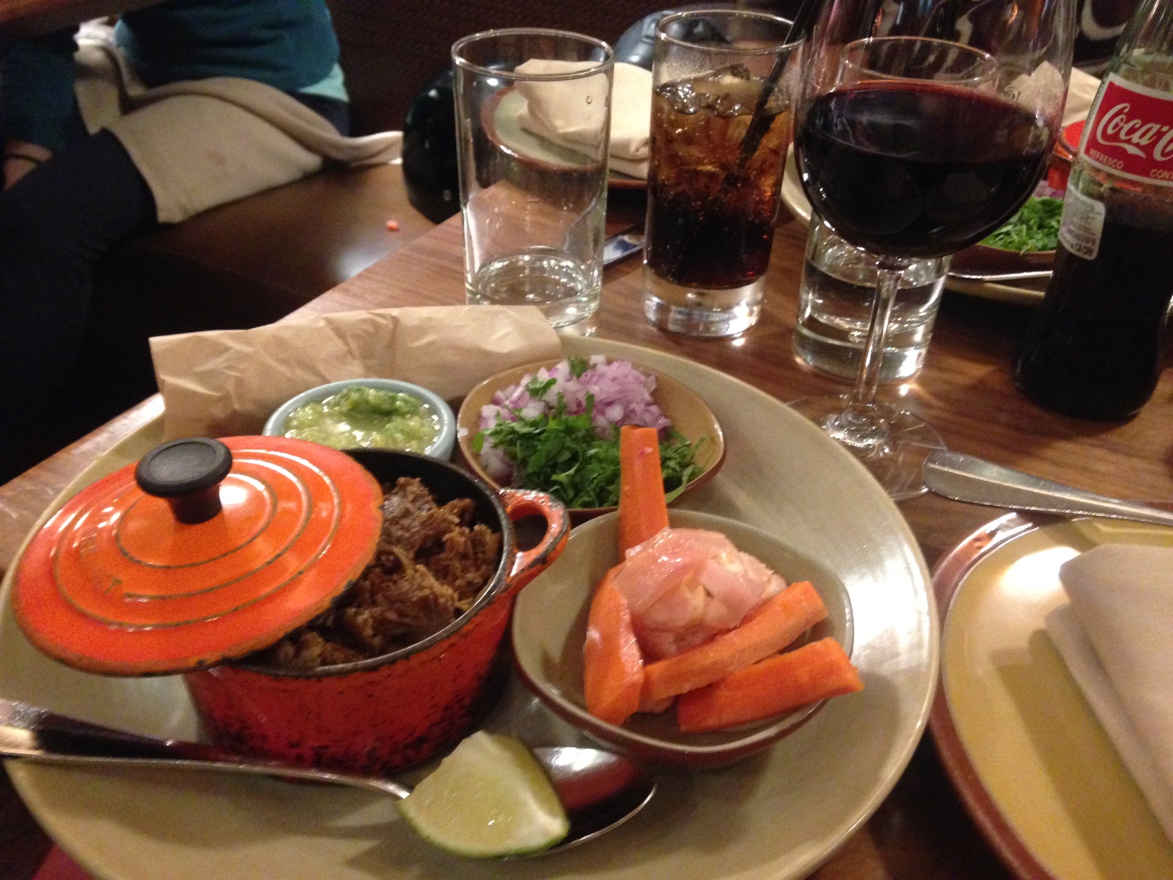 A red enamelled pot of stew with carrots and a glass of red wine