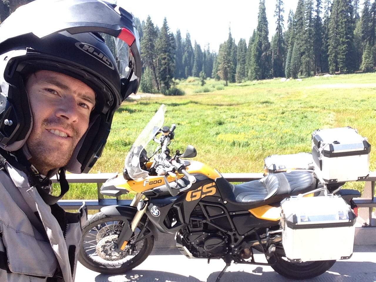 A helmet selfie beside the motorcycle at the meadow