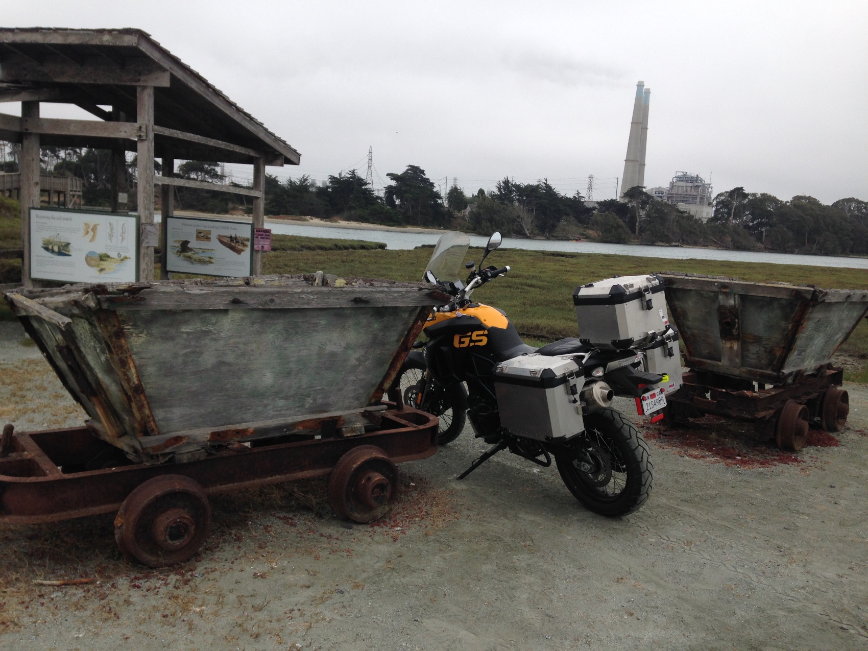 The motorcycle parked between two rusted mine carts at Moss Landing