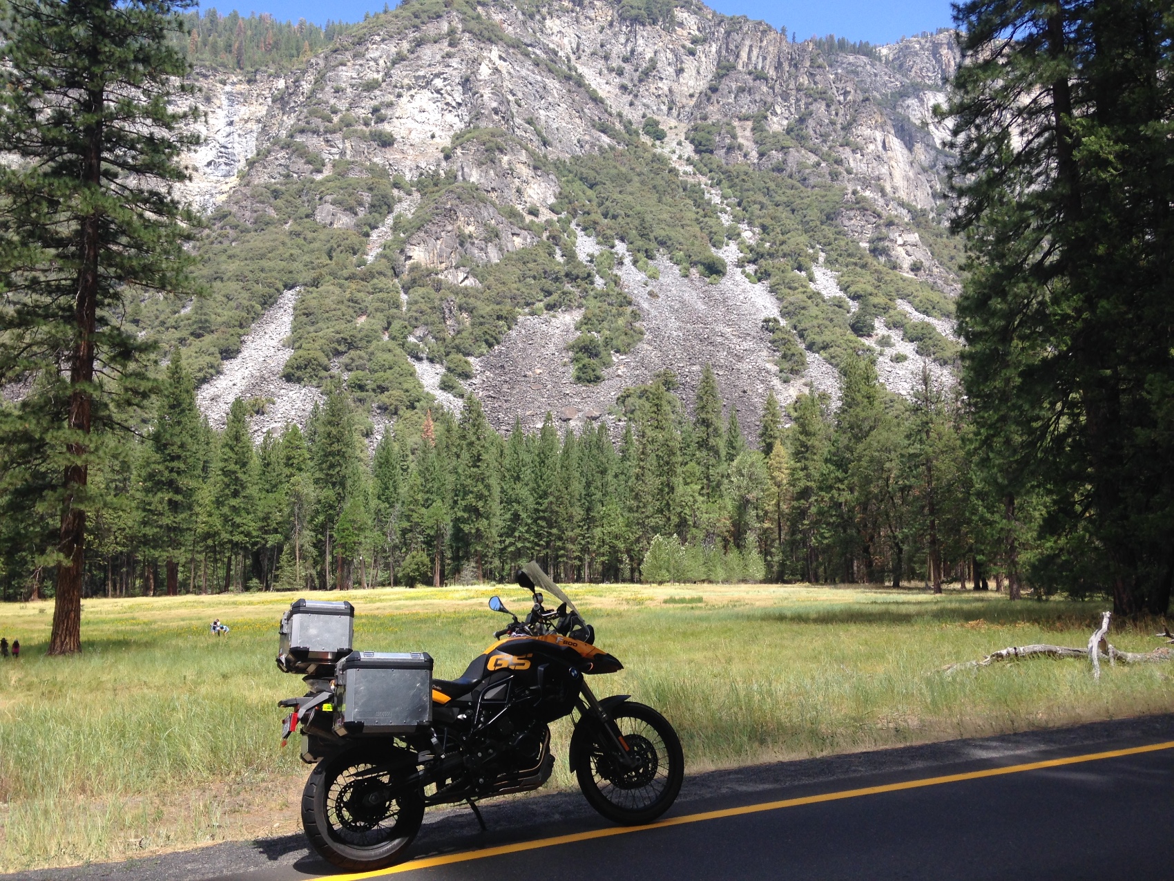 The motorcycle on the roadside with a meadow and El Capitan behind