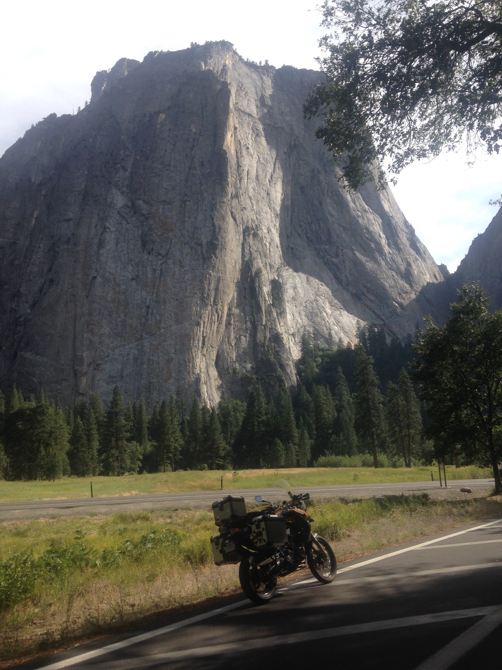 The motorcycle on a valley road below a granite wall