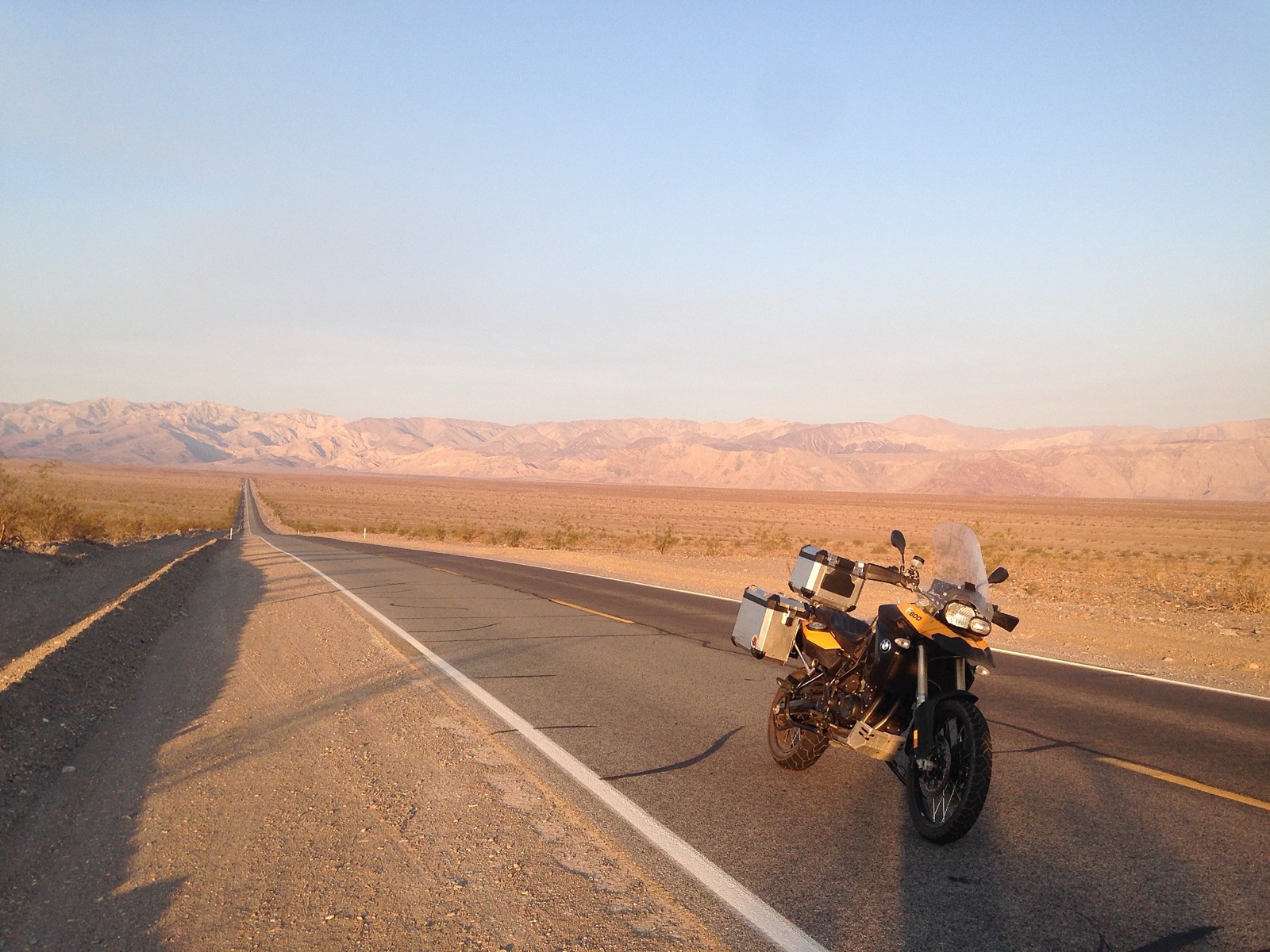 The motorcycle on an empty desert road with mountains behind