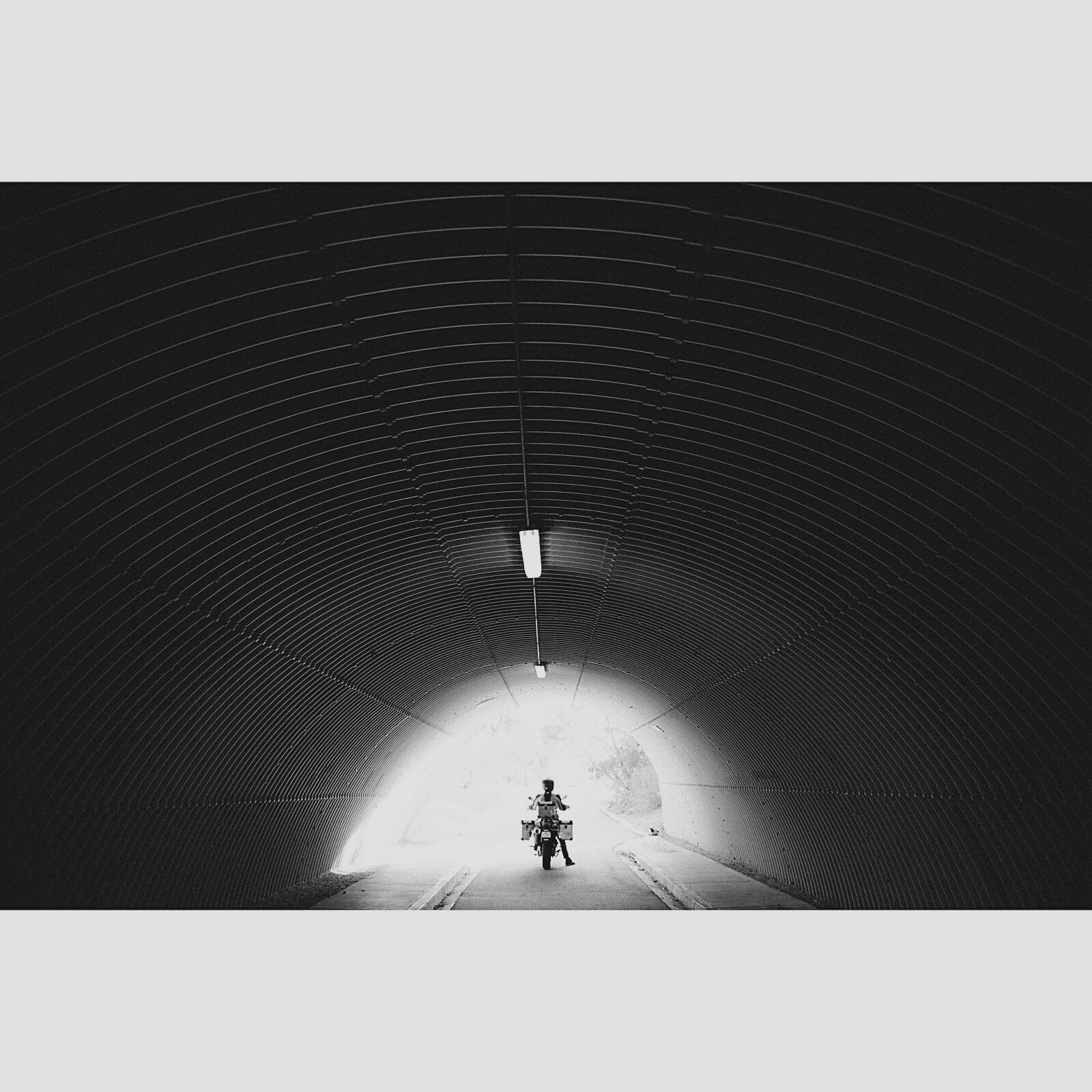 A silhouette of the motorcycle in a lit tunnel