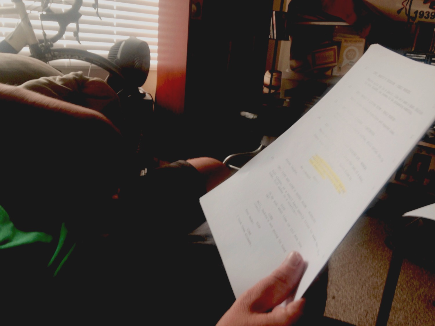 Script pages held in a hand in a living room