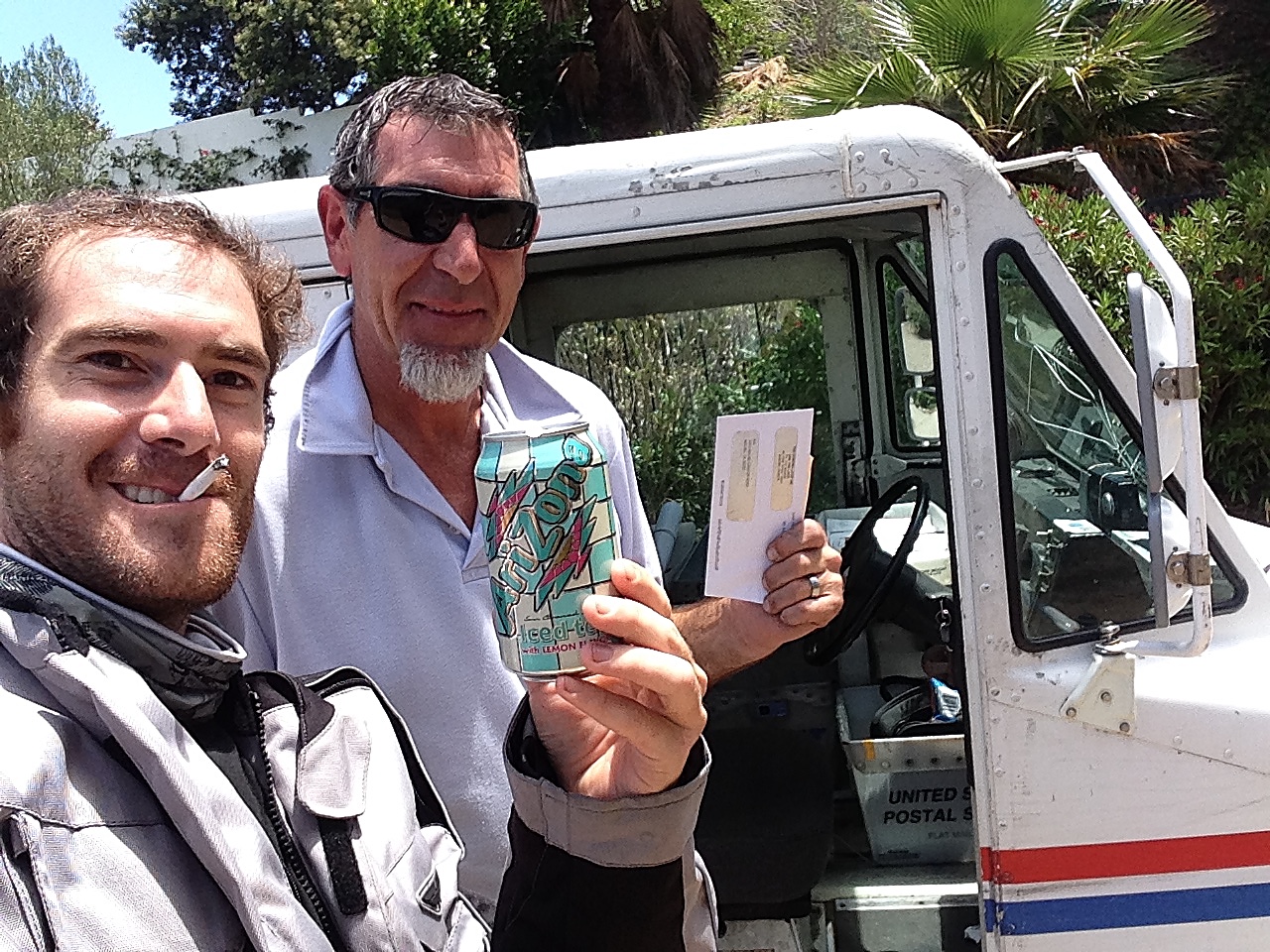 A postman in his mail truck handing over a beer