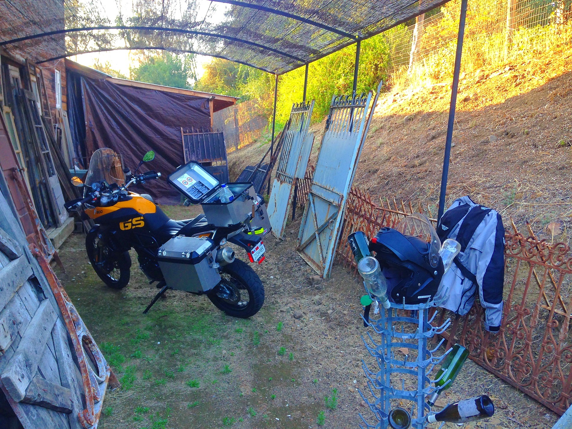 The motorcycle under a corrugated roof among old doors and fencing