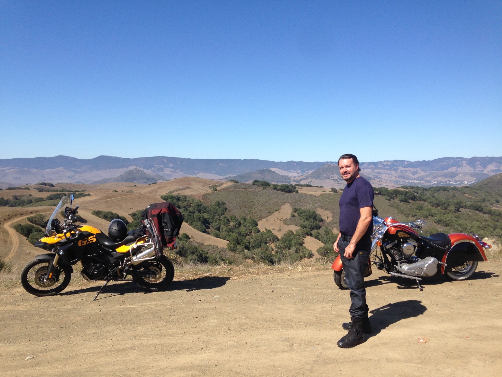 Two motorcycles on a dirt lookout above a valley