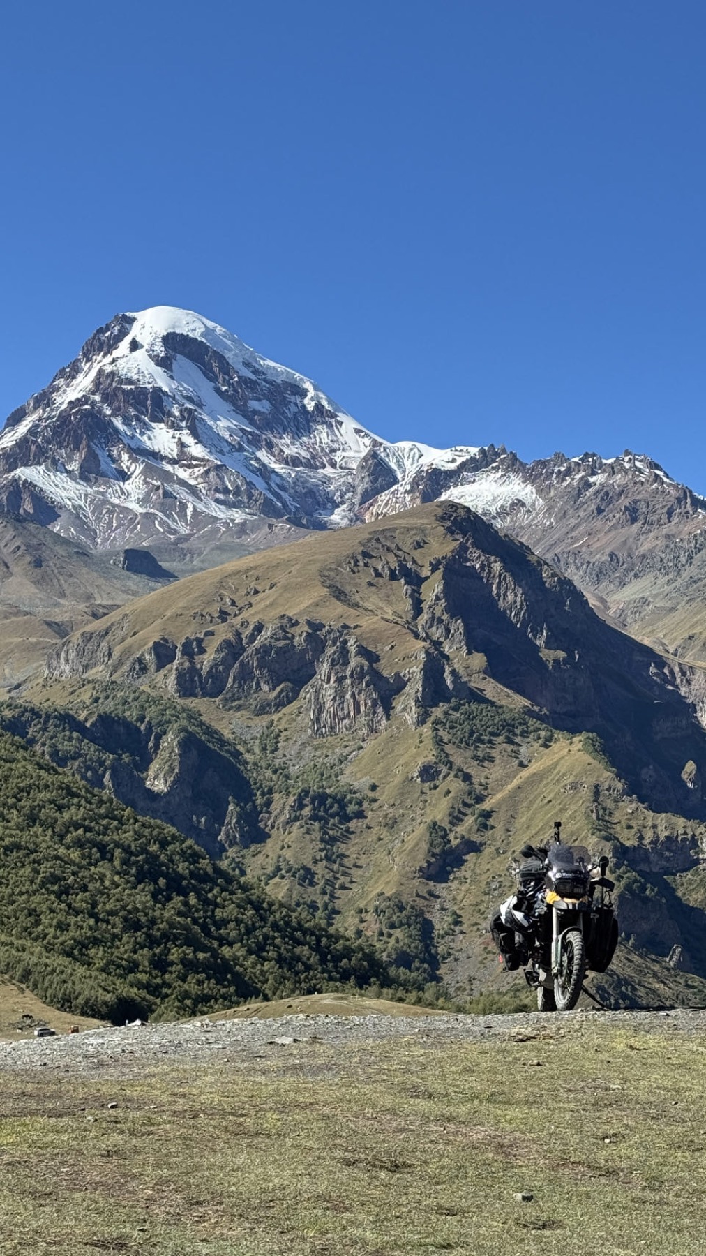 The motorcycle on a mountain road below snow peaks