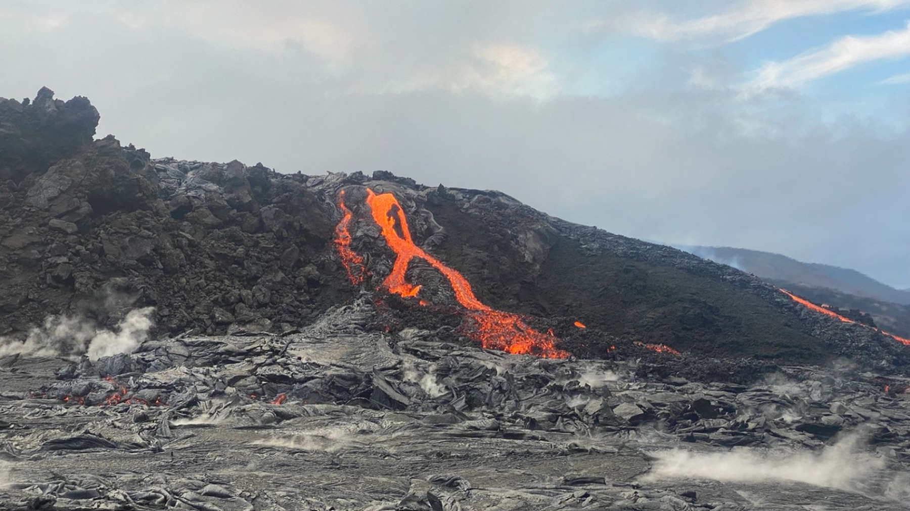 A river of orange lava crossing a black lava field