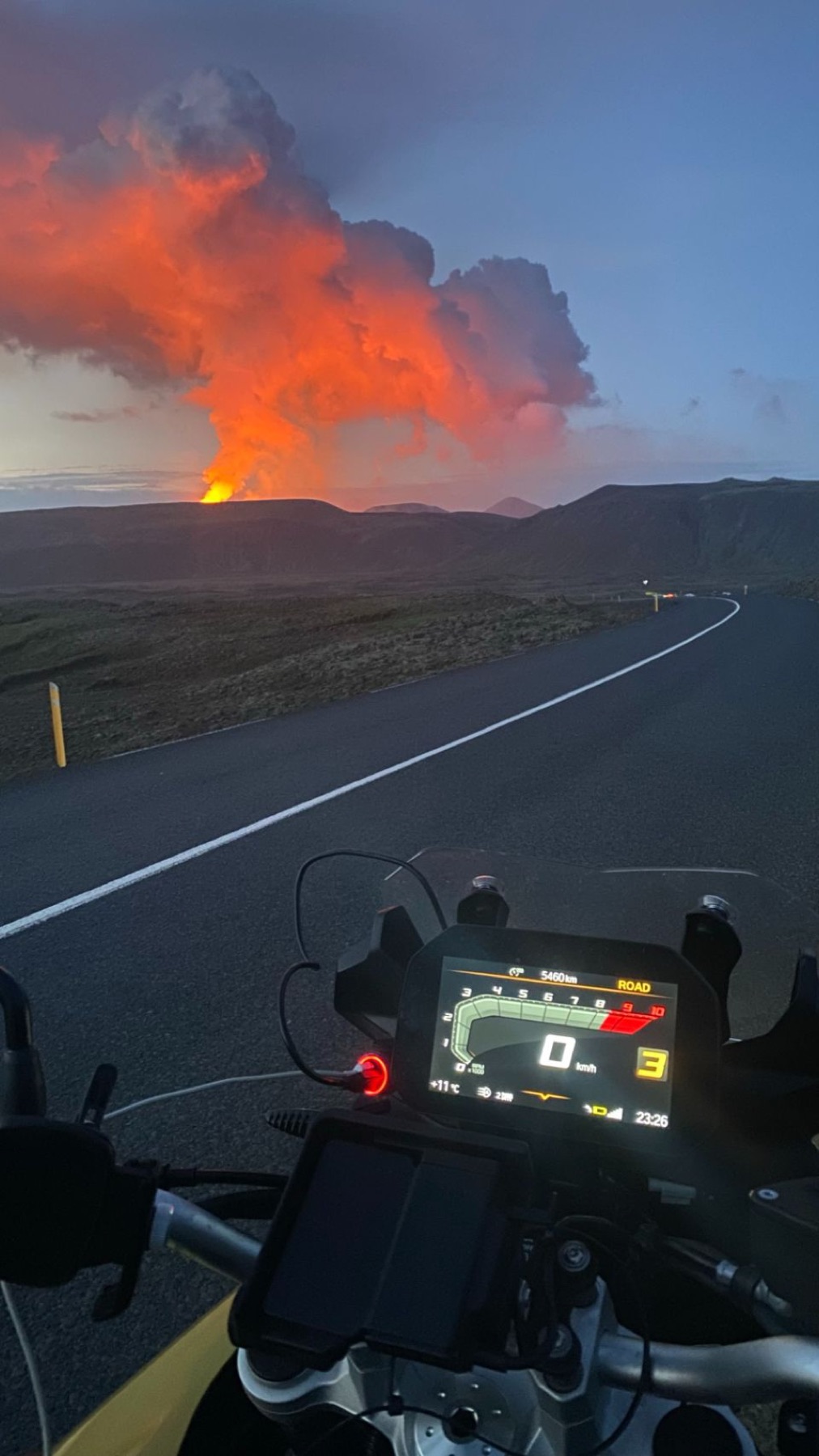 The motorcycle instrument panel with the erupting volcano ahead on the road