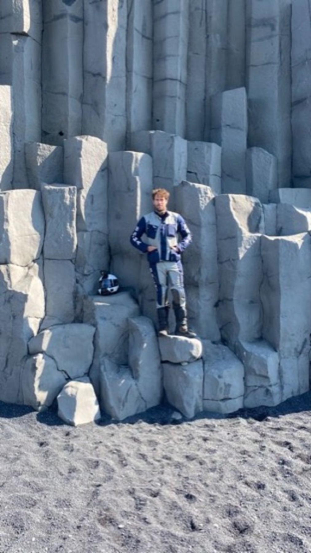Rodrigo standing among hexagonal basalt columns on a black sand beach