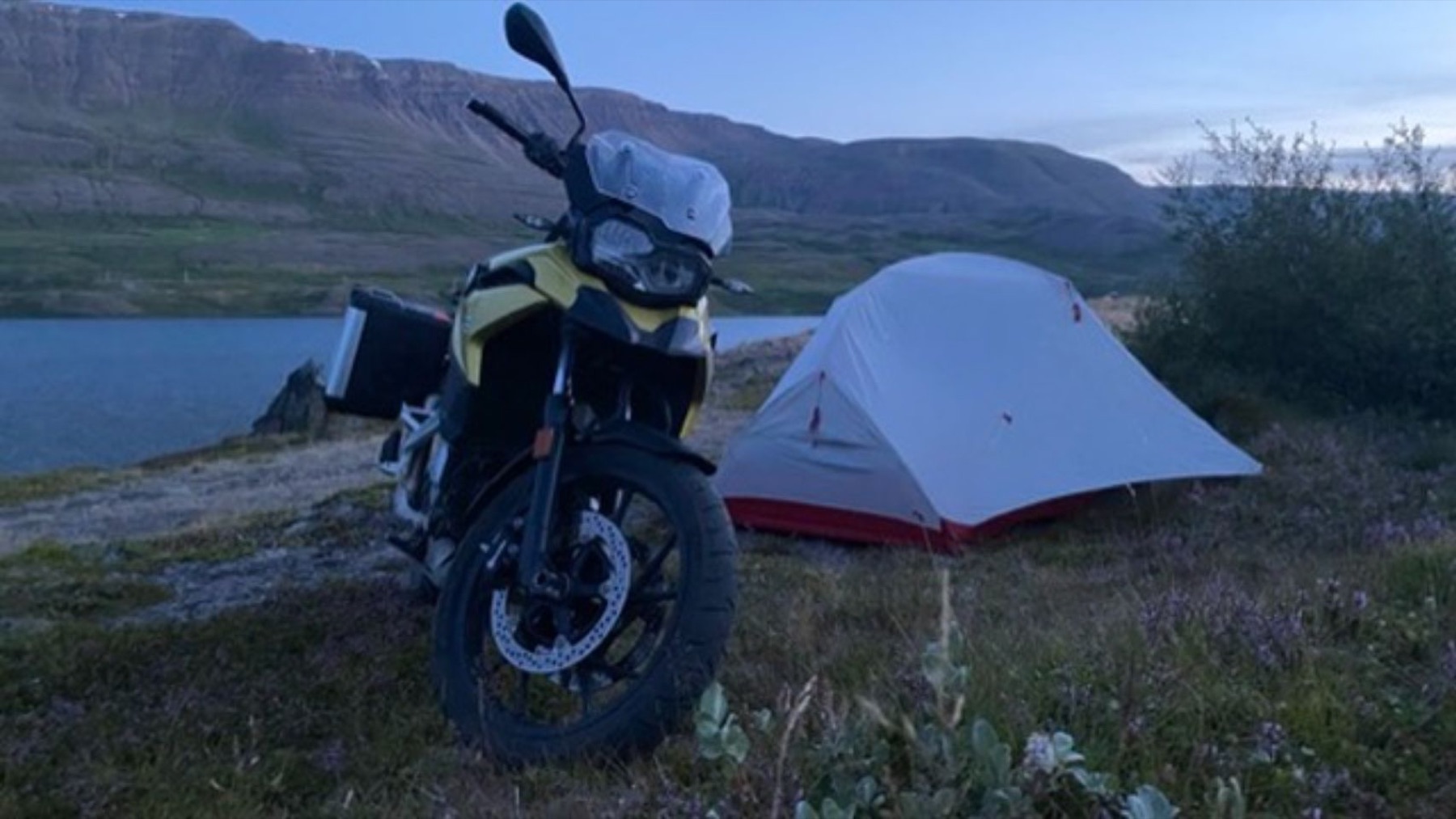 The tent pitched beside the bike near a fjord