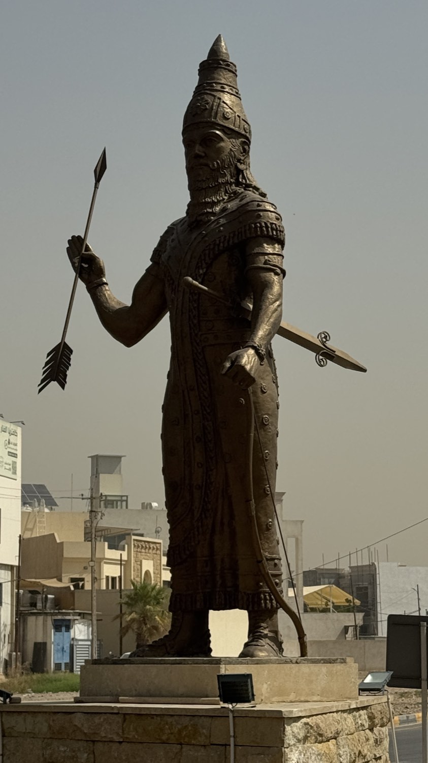 A large bronze statue of an Assyrian king holding arrows