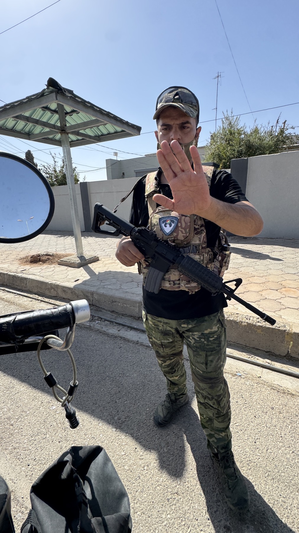 A Peshmerga soldier waving beside the loaded motorcycle
