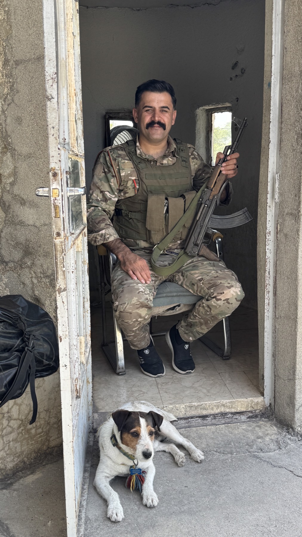 A soldier sitting in a doorway with Jacko lying beside him