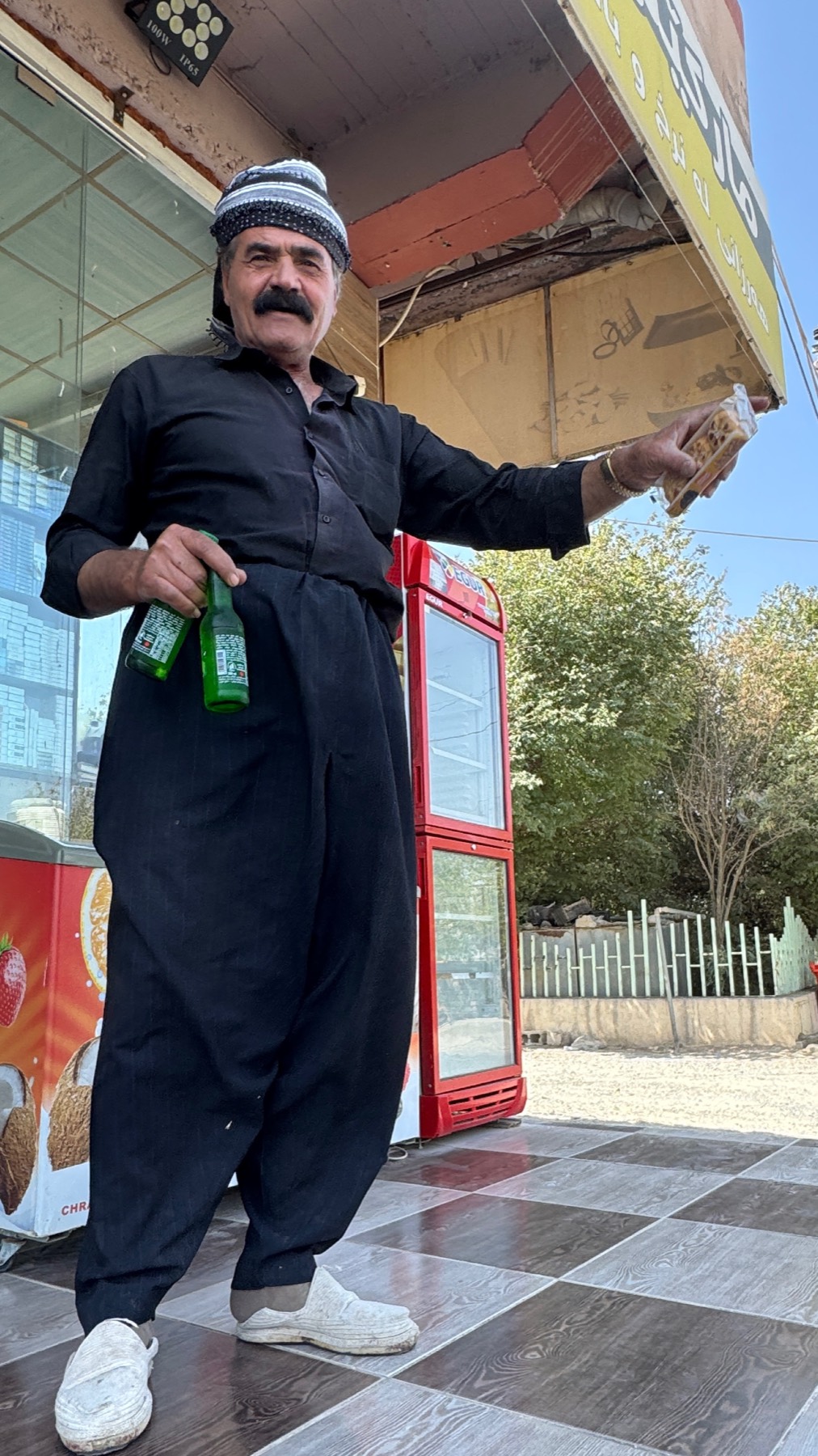 A man in traditional Kurdish dress outside a shop