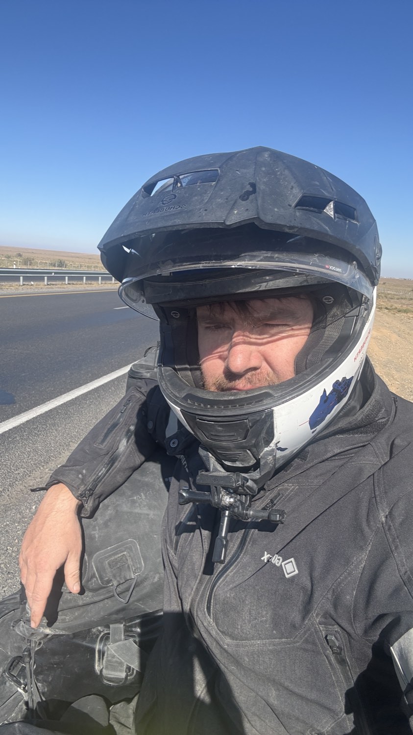 Rodrigo in his helmet at the roadside, the empty steppe behind him