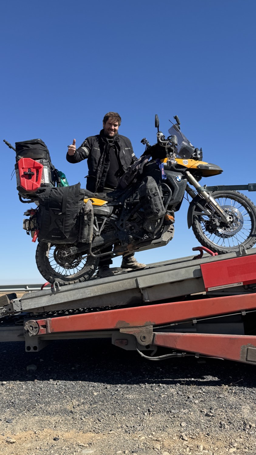 The loaded motorcycle up on the ramp of a tow lorry, Rodrigo giving a thumbs up