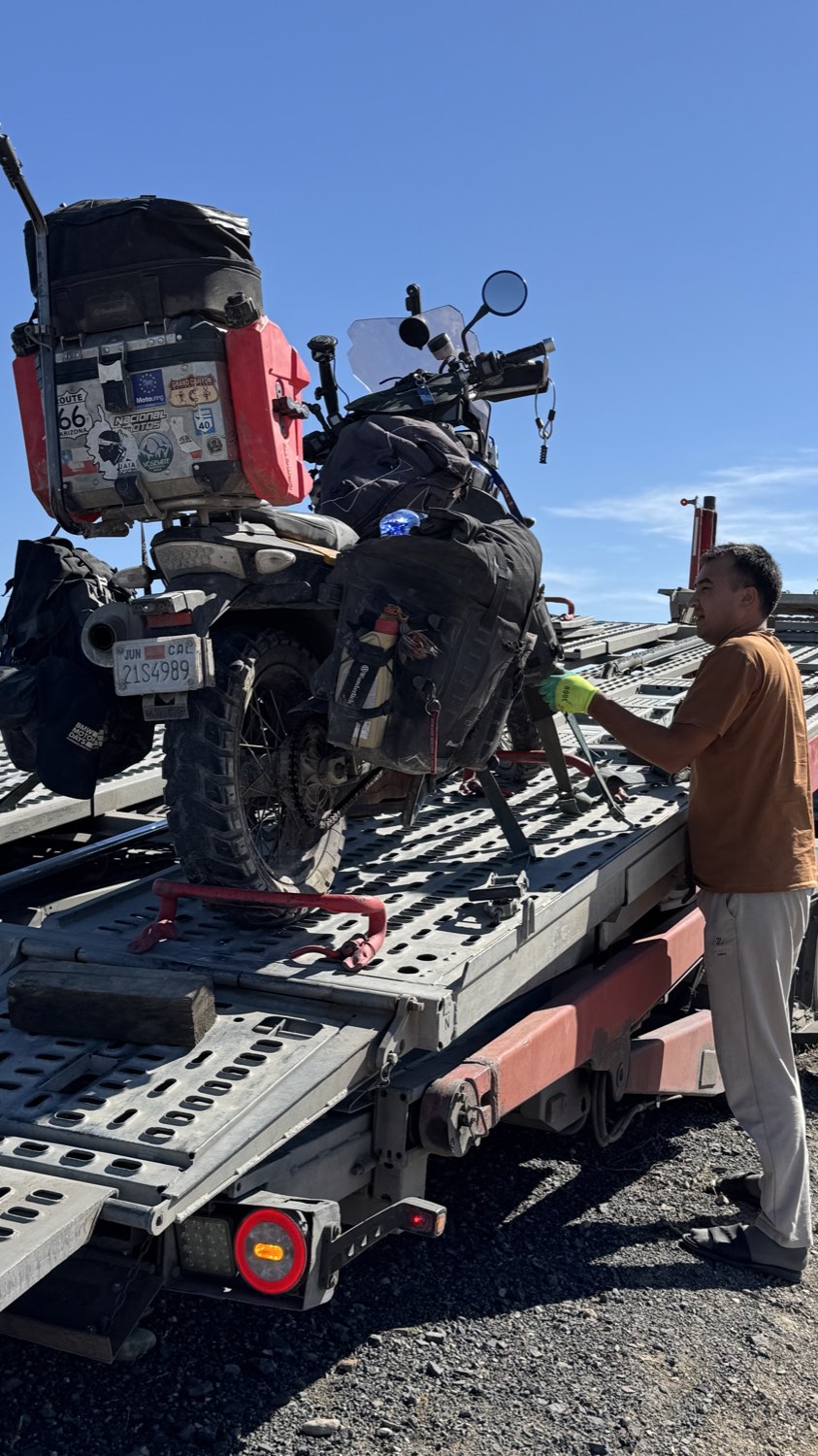 The driver strapping the motorcycle down on the flatbed