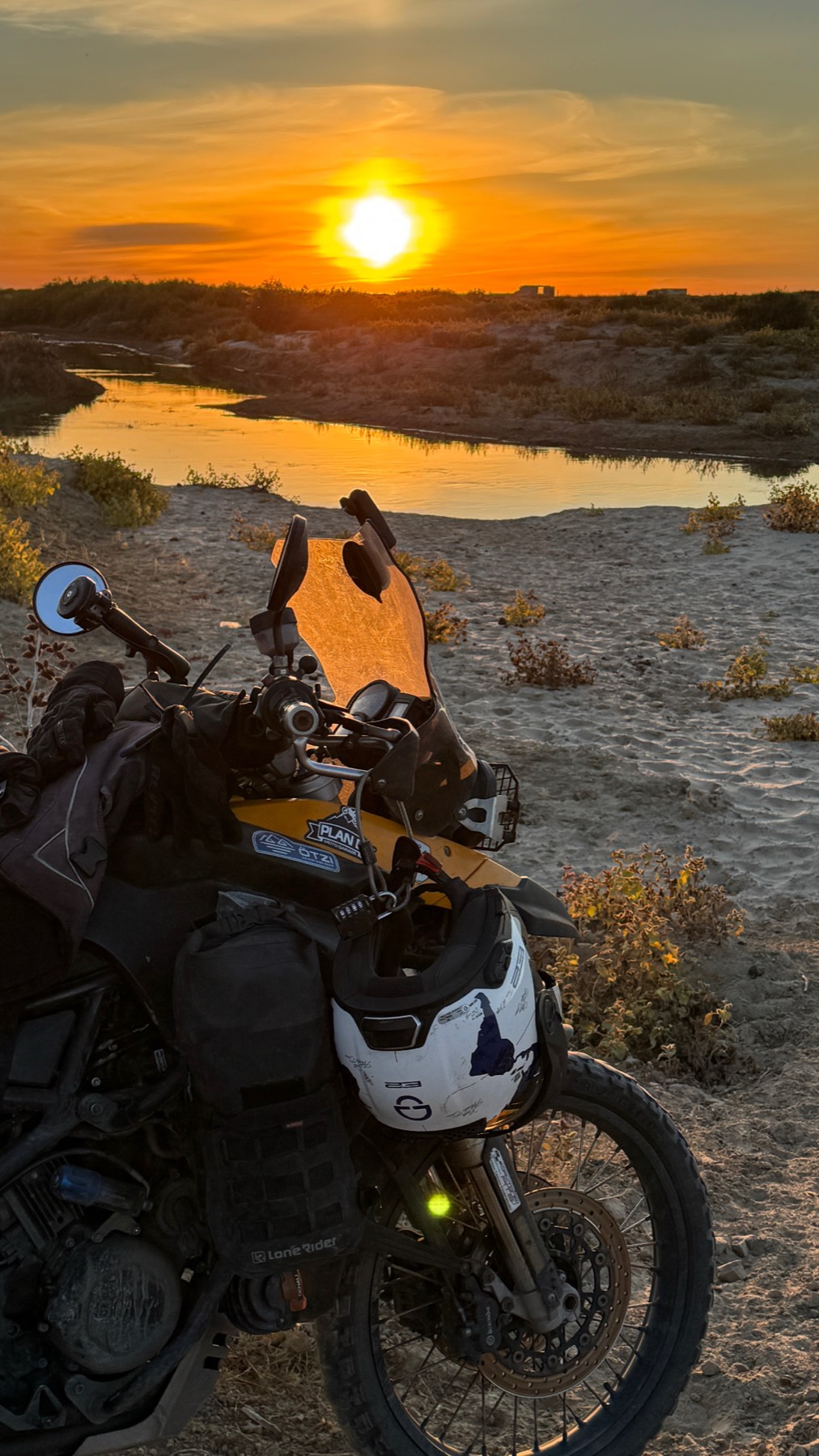 The loaded motorcycle beside a river at sunset