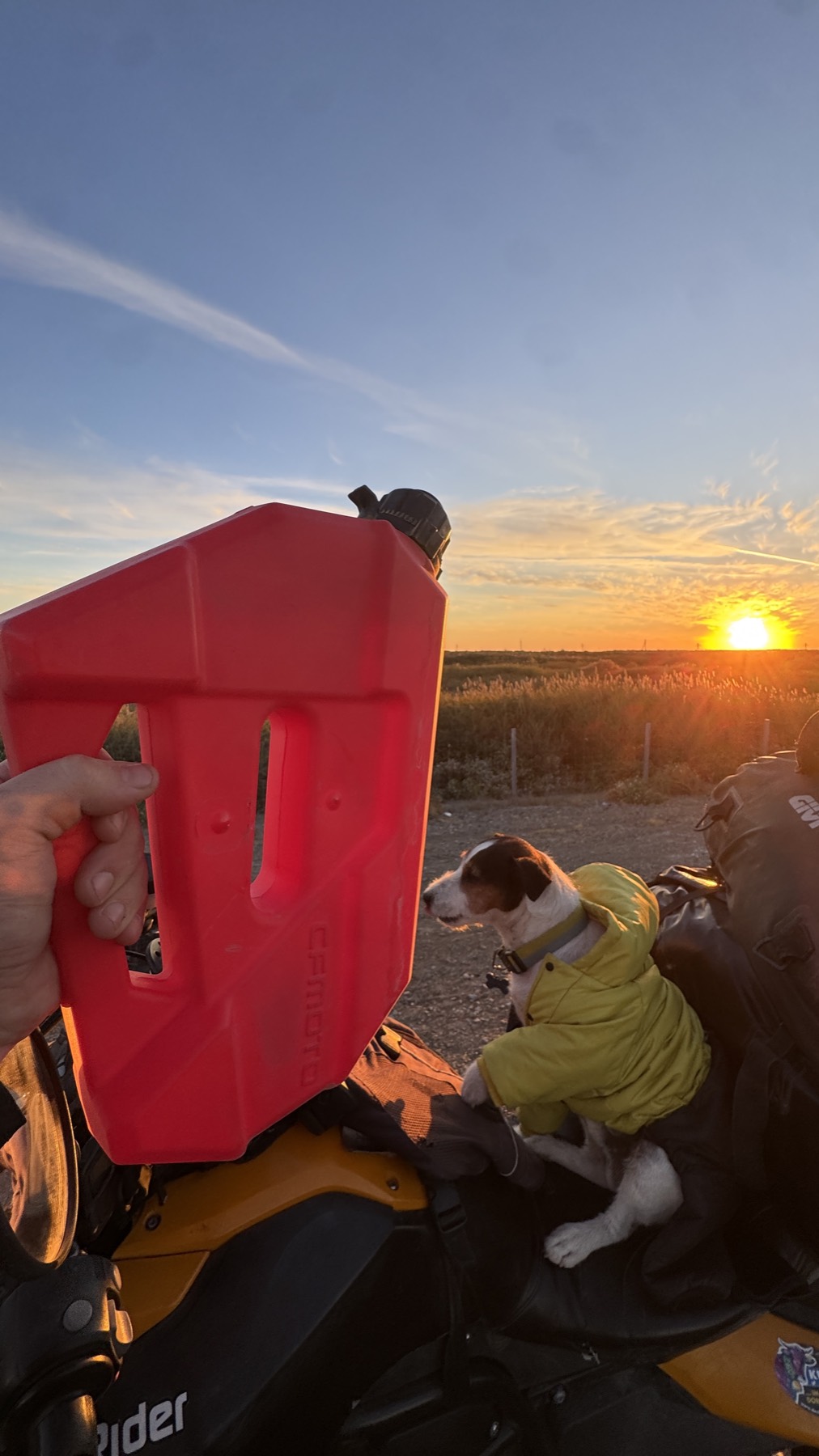 A red spare fuel can held up beside Jacko at sunset