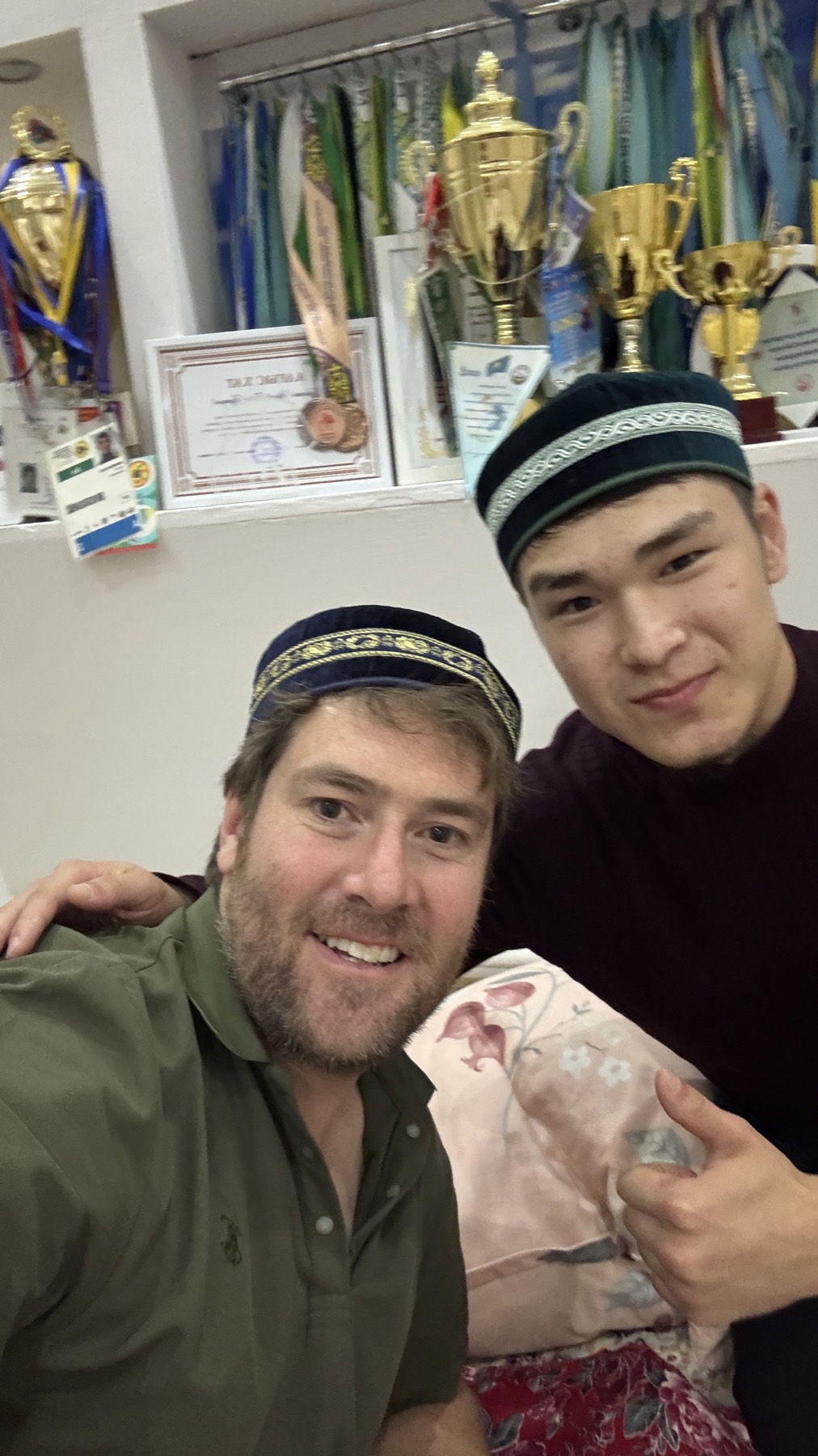 Rodrigo wearing a traditional cap beside a young Kazakh man