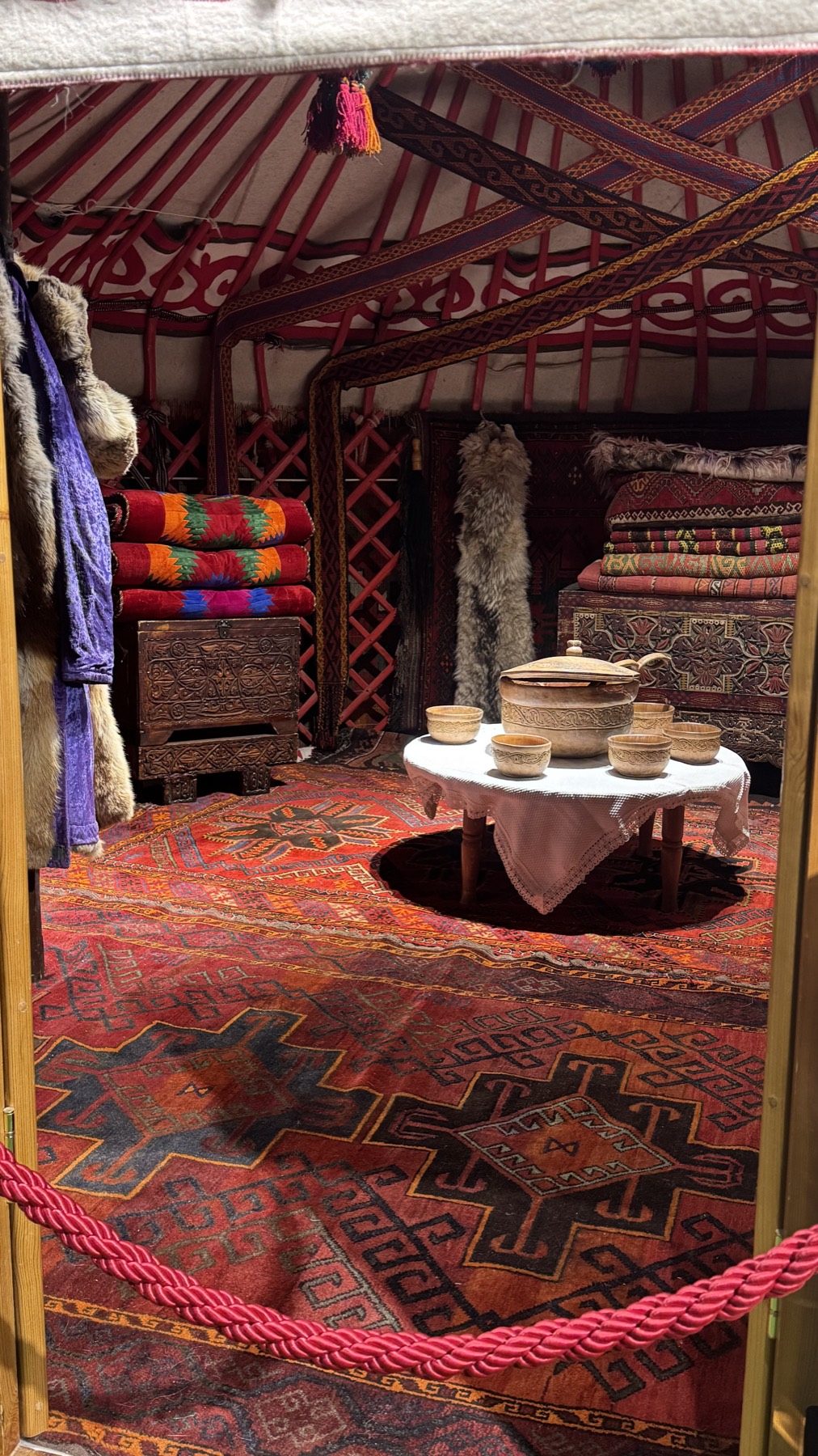 The interior of a Kazakh yurt with carpets, chests and a low table