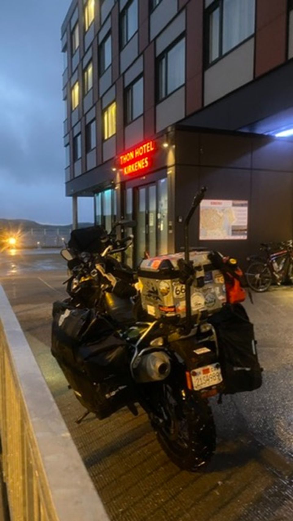 The loaded motorcycle parked outside the hotel in Kirkenes at dusk