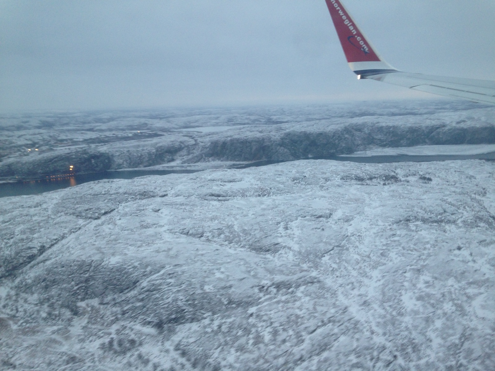The wing of an aircraft over the frozen Arctic coast