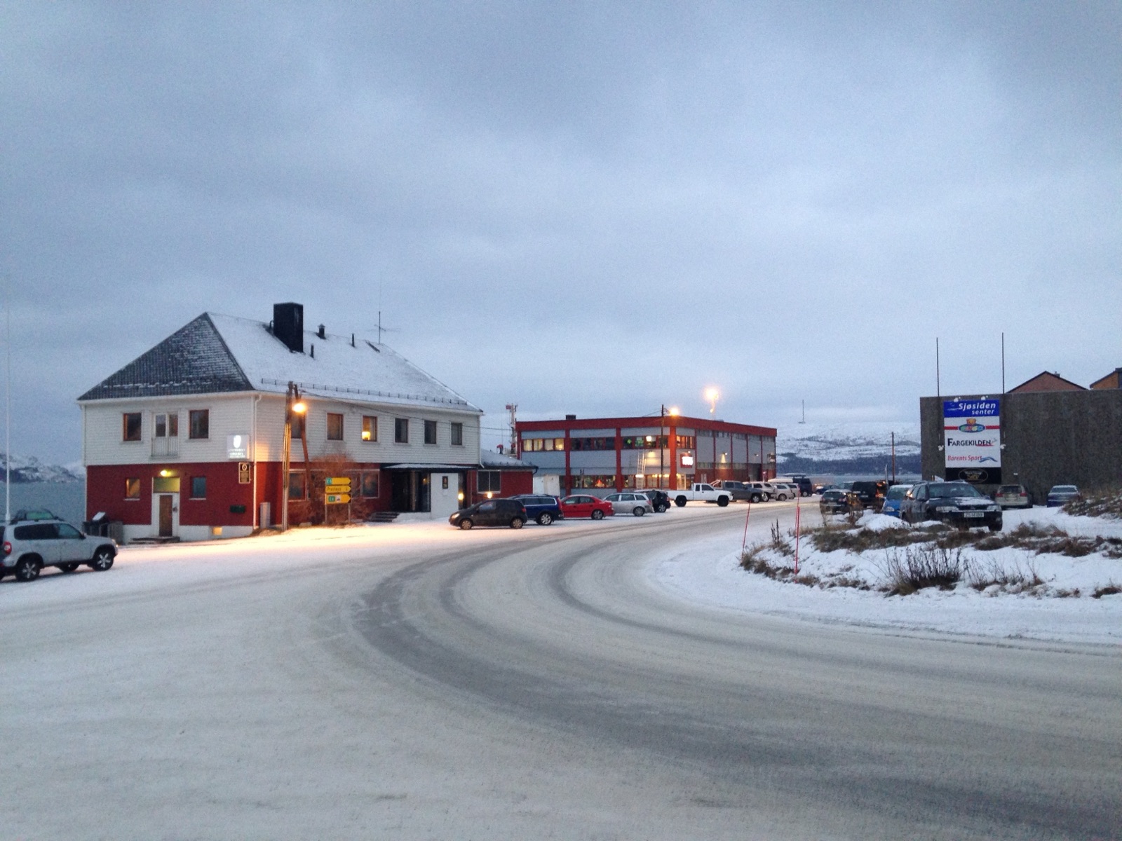 A snowy street in Kirkenes with a red timber house