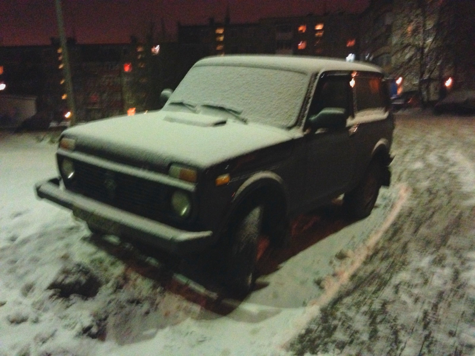 A Lada Niva covered in snow at night in Murmansk