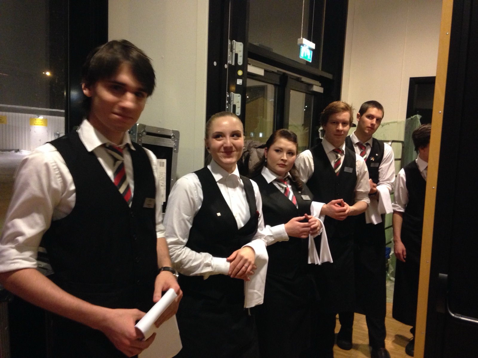 Six young waiters lined up in uniform