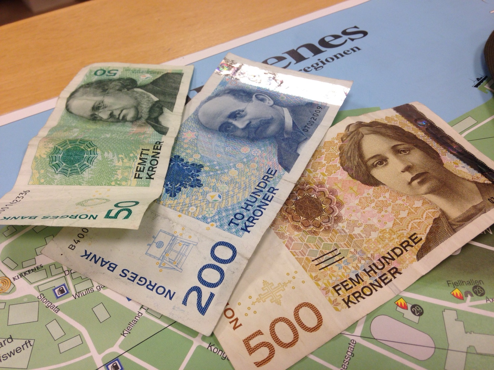 Norwegian banknotes on top of a map of Kirkenes