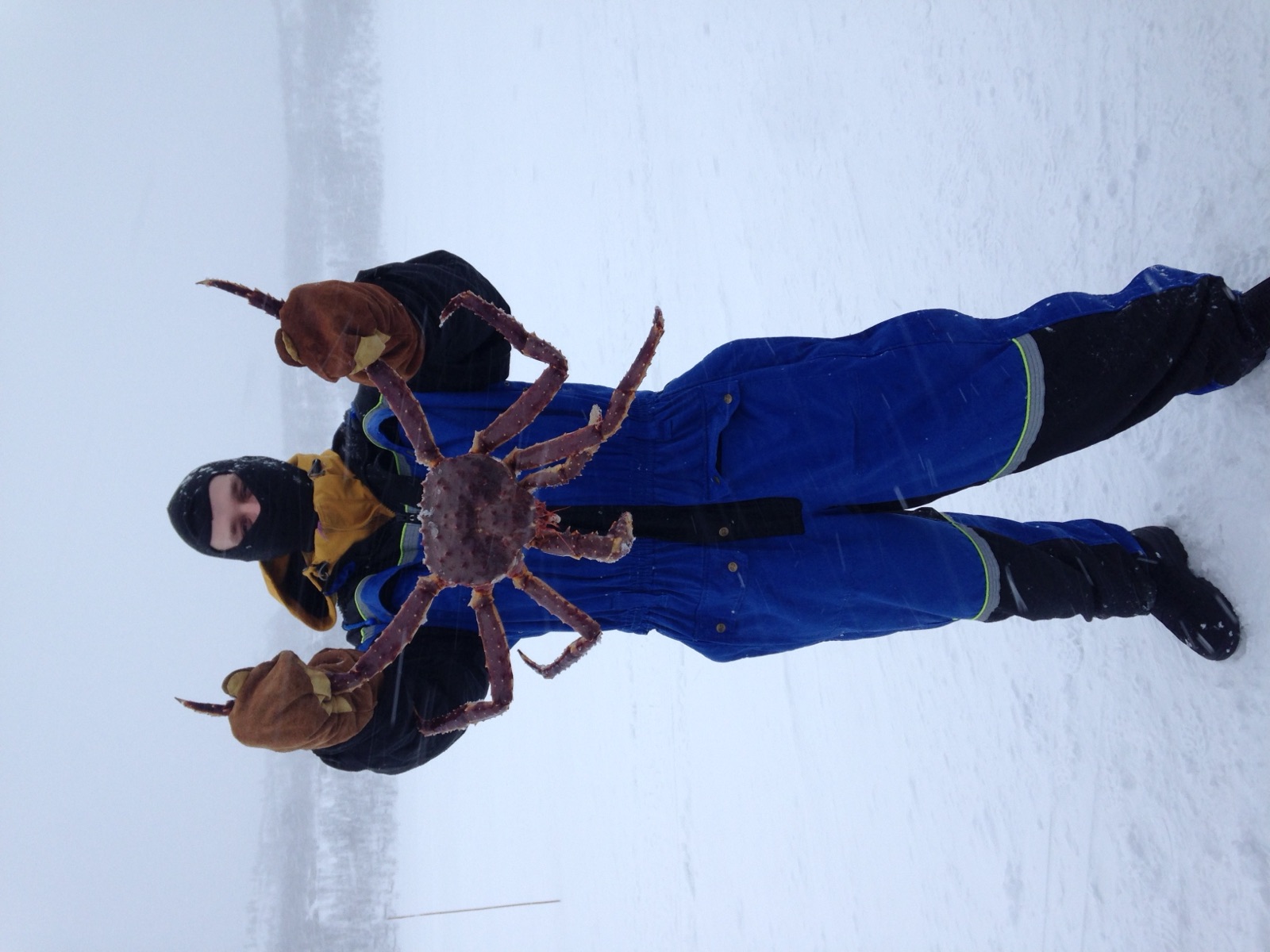 Rodrigo standing on the ice holding up a king crab