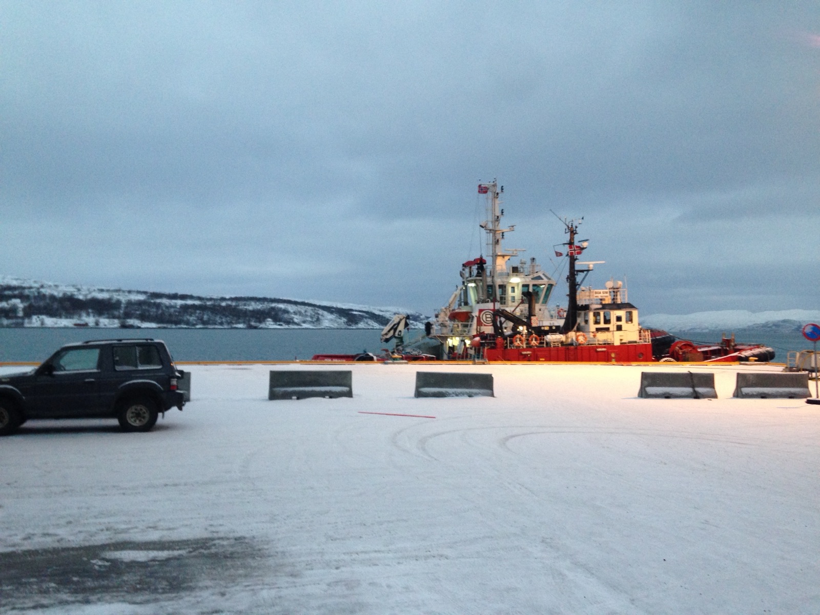 A red and white tugboat moored at the frozen quay in Kirkenes