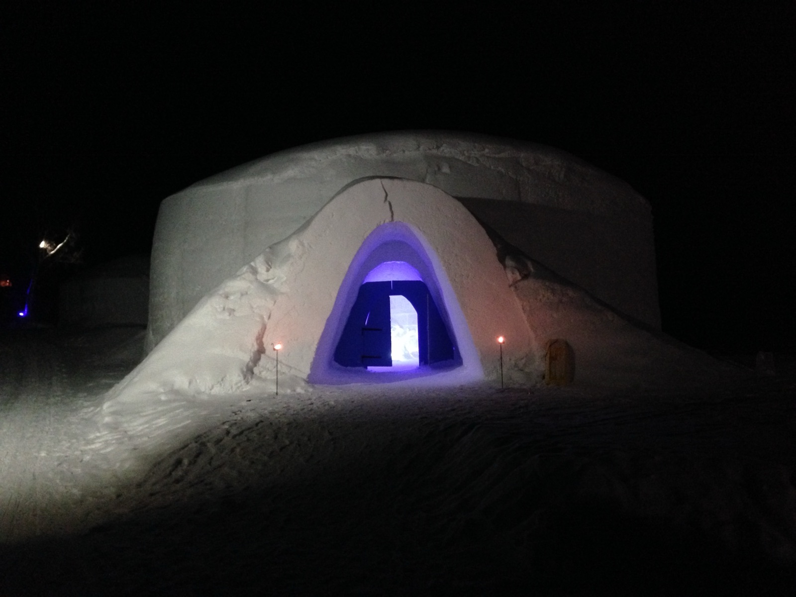 The lit entrance of the Snowhotel Kirkenes at night