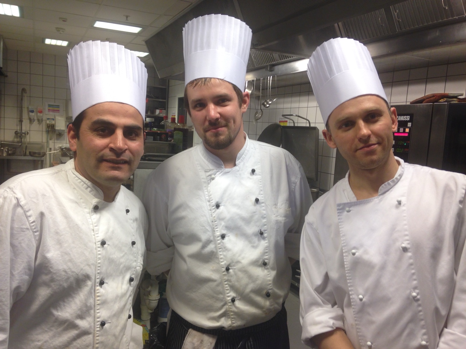 Three cooks in tall white hats in the hotel kitchen
