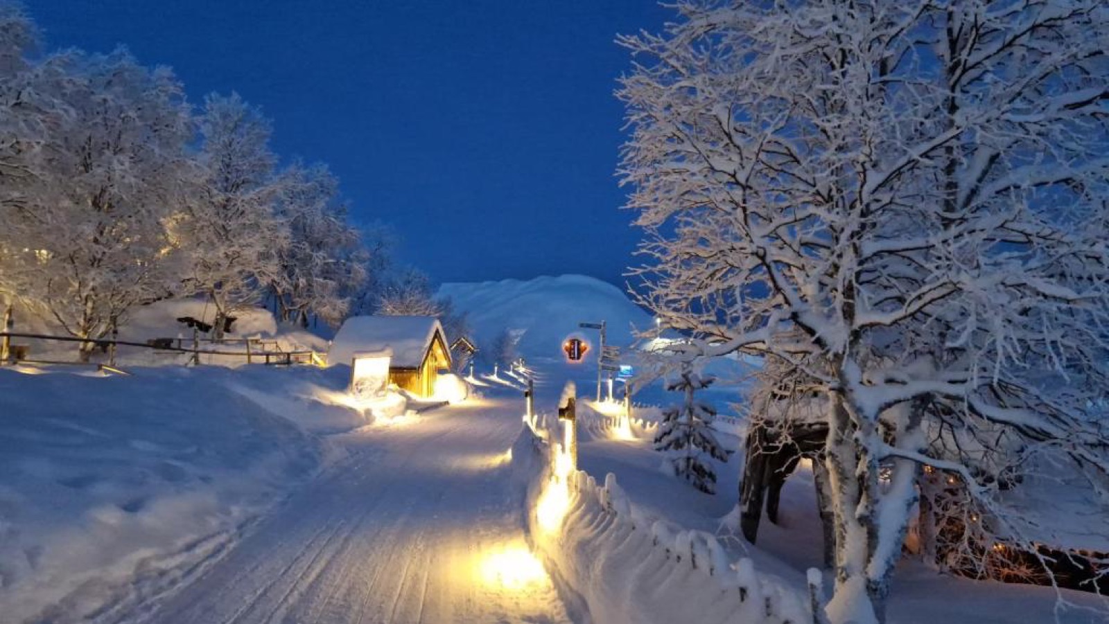 A snow-covered lane in Kirkenes lit by lanterns at night