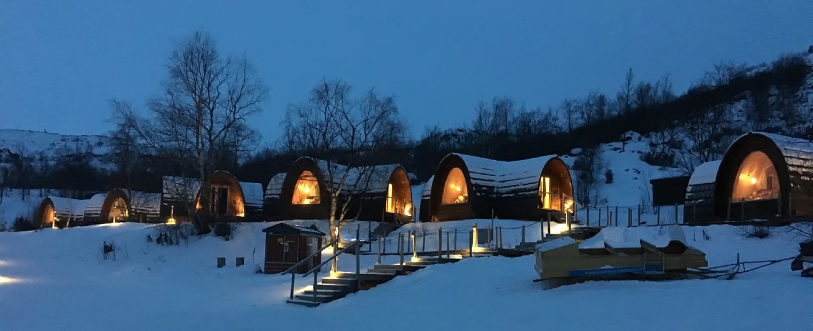 Lit cabins in the snow at dusk