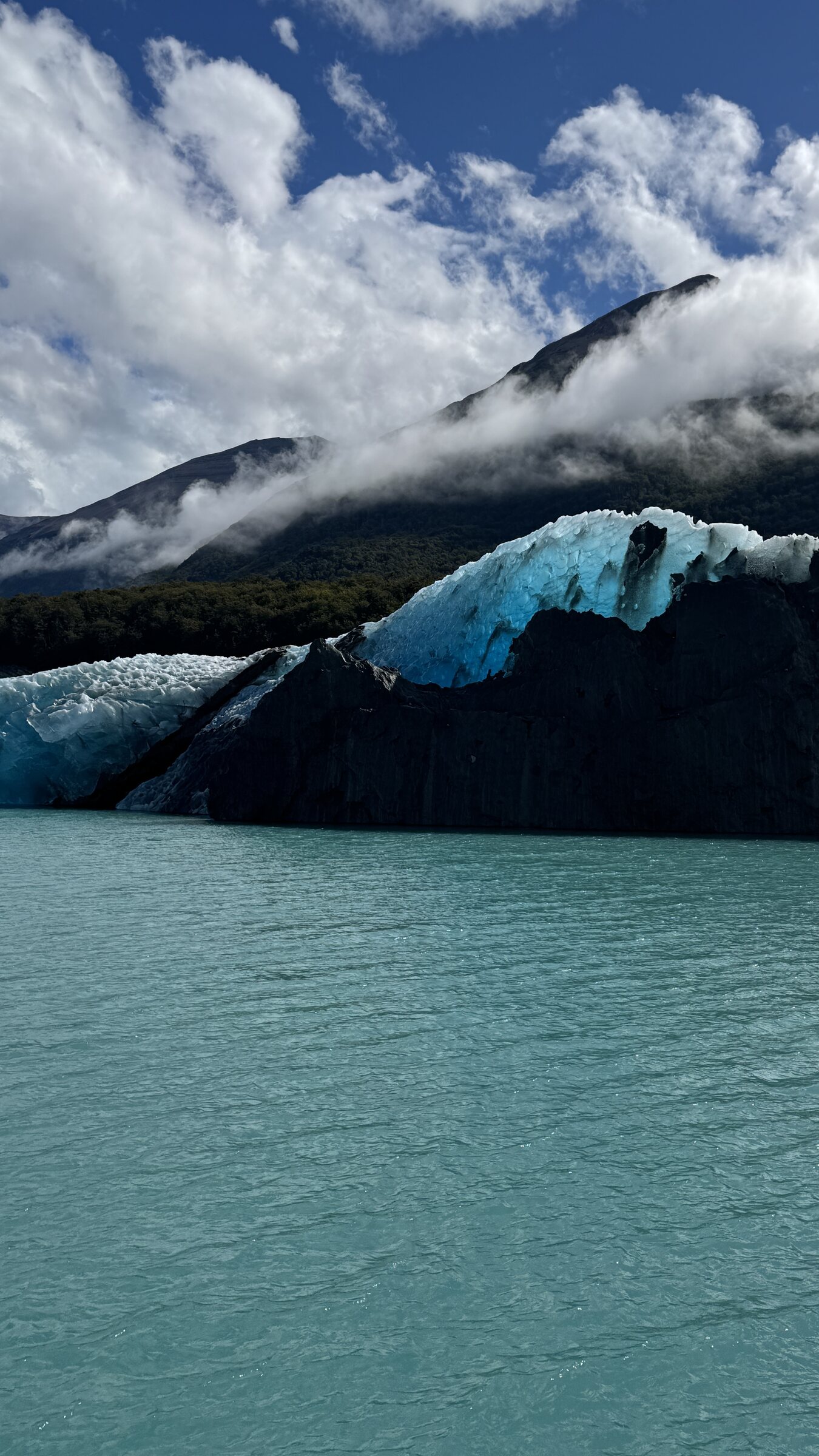 Blue glacial ice and dark mountain forest