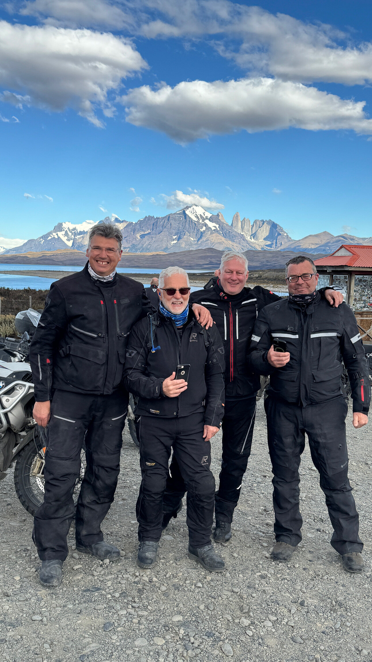 Four expedition riders in front of the Torres del Paine mountains