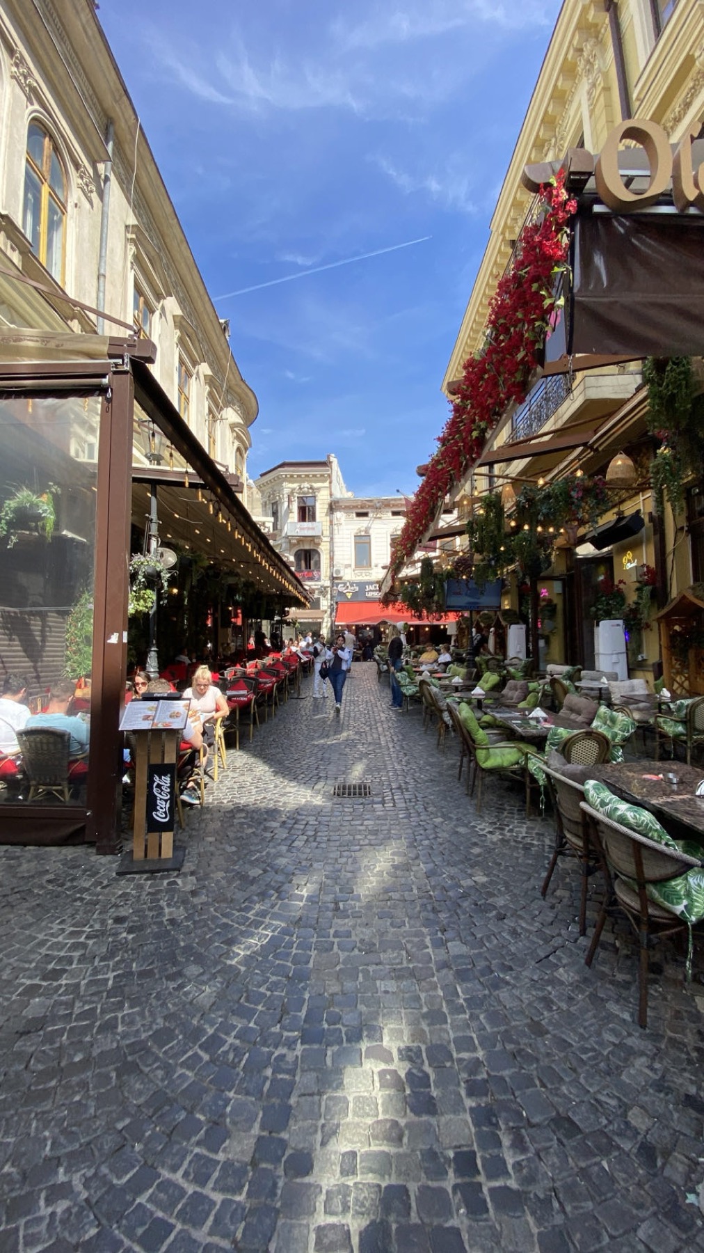 A cobbled street in the old town of Bucharest lined with restaurant terraces