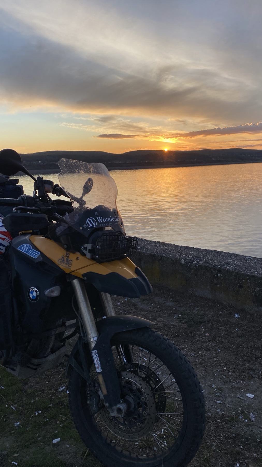 The loaded motorcycle on the beach with the sun going down over the water