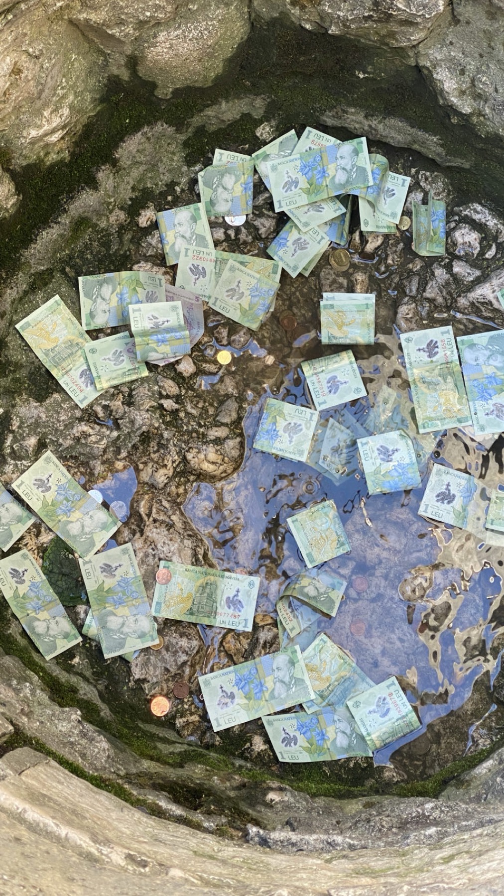 A stone wishing well filled with banknotes and coins